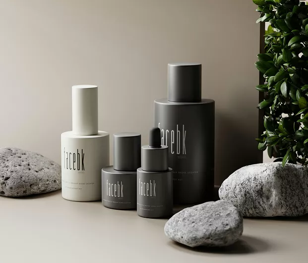 Minimalist skincare bottles in neutral gray and white packaging arranged with smooth stones and greenery on a beige background, creating a calm, modern aesthetic.